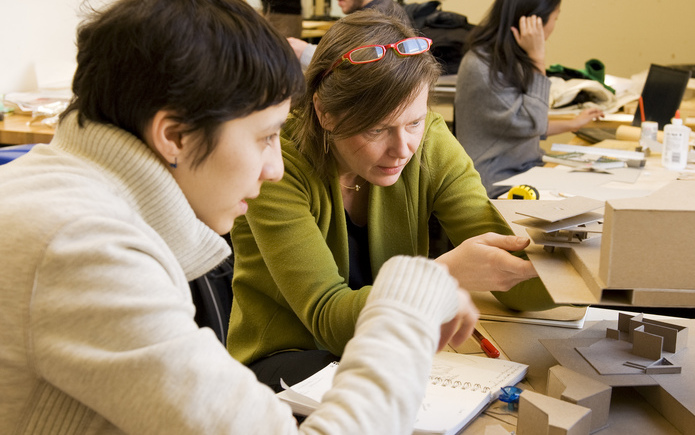 A faculty member and a student look at a model.